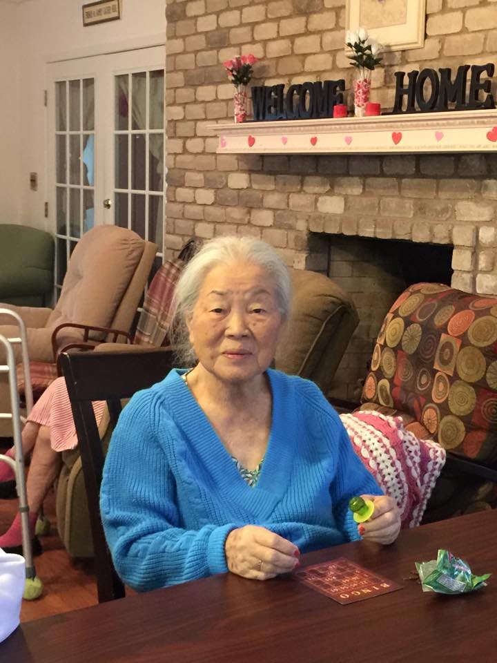 An elderly woman sitting in a cozy living room, engaged in knitting.