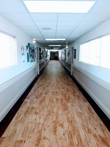 A well-lit hallway featuring artwork on the walls and a wooden floor.