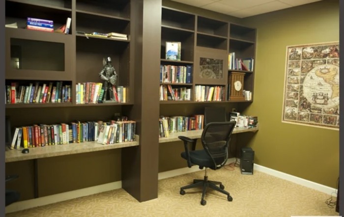 A neatly organized home office with bookshelves, a comfortable chair, and a desk.
