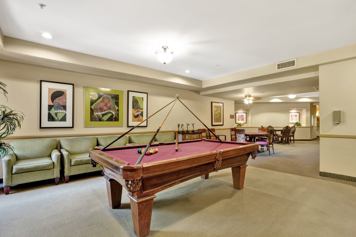 A well-furnished recreation room featuring a pool table, comfortable seating, and framed artwork on the walls.
