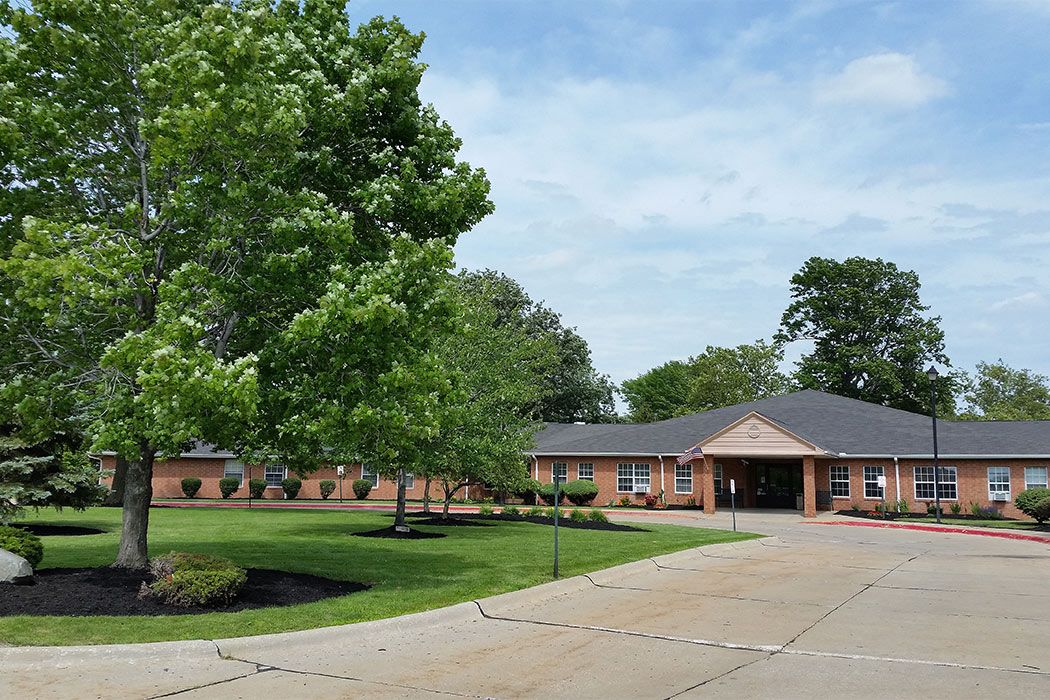 A view of a brick school building surrounded by trees and a driveway.