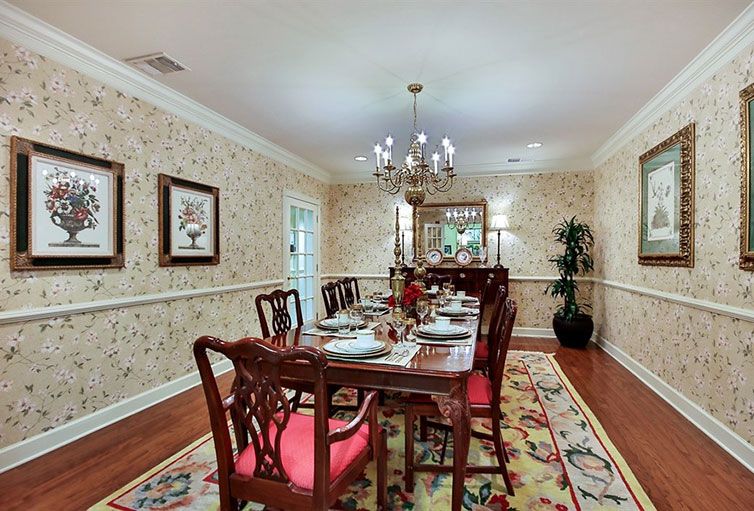 A traditional dining room with a beautifully set table, chandelier, and elegant wallpaper.
