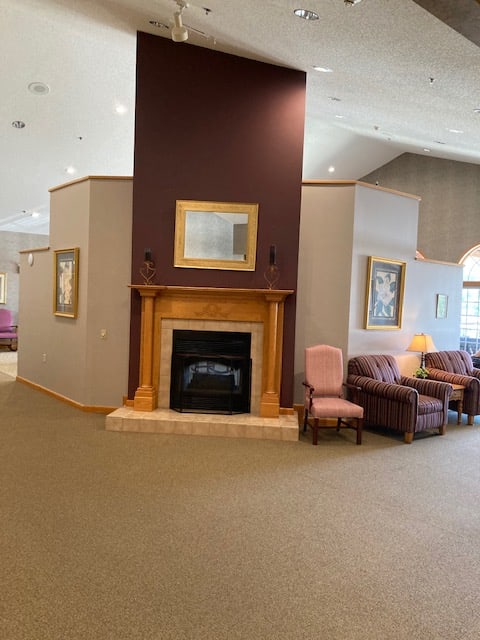 A cozy interior living space featuring a central fireplace with surrounding chairs and couches.