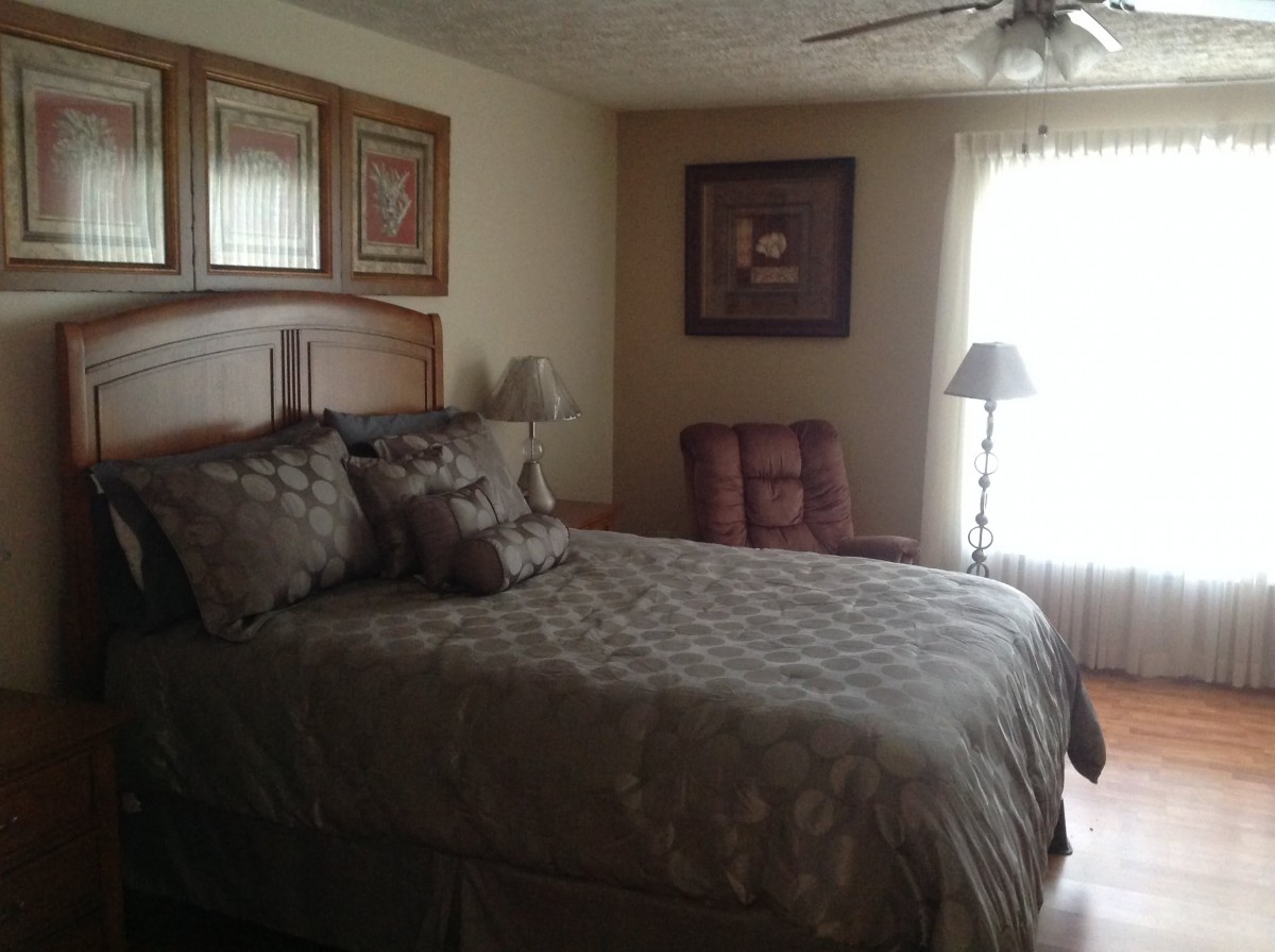A cozy bedroom with a large bed, decorative pillows, and a standing lamp.