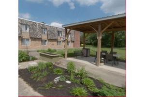 A landscaped garden area with a gazebo and outdoor seating near an apartment building.