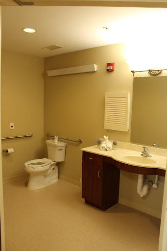 A clean and accessible bathroom featuring a toilet, sink, and large mirror.