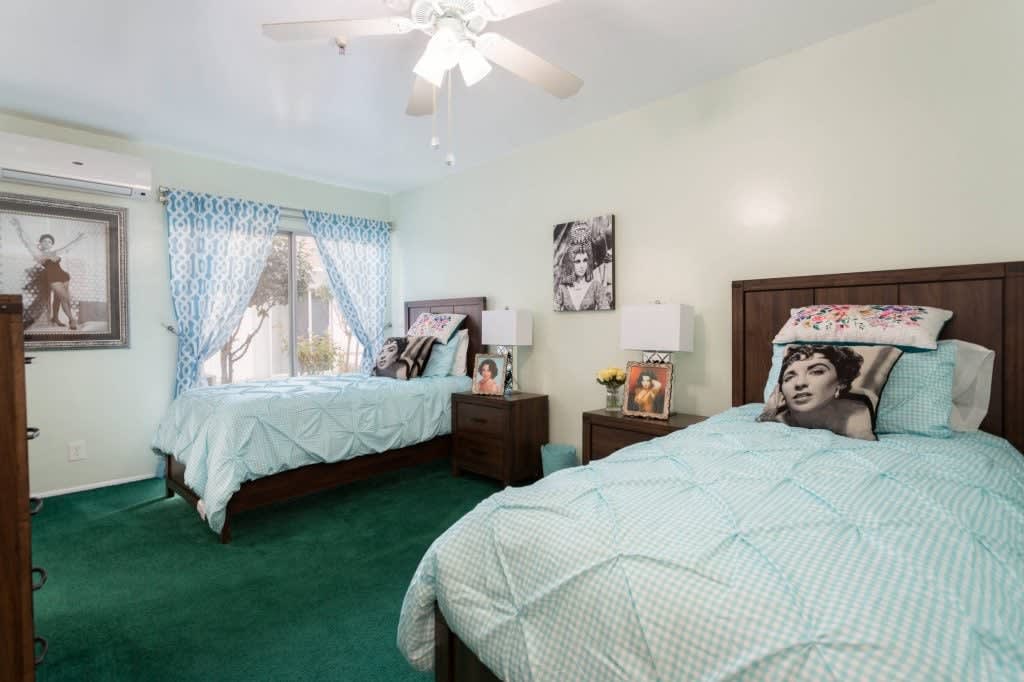 A cozy bedroom with two beds, green carpet, and decorative elements.