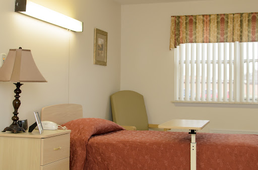 A neatly arranged hospital room featuring a bed, chair, and bedside table.