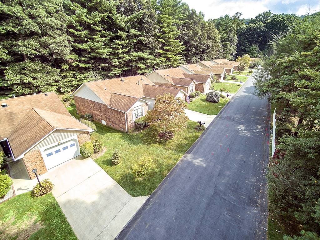 An aerial view of a quiet residential neighborhood lined with houses and surrounded by trees.