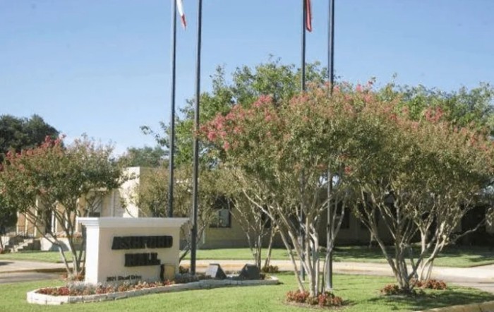 A landscaped area with flagpoles and trees next to a building.