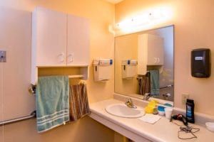 A clean bathroom with a sink, a large mirror, and neatly hung towels.