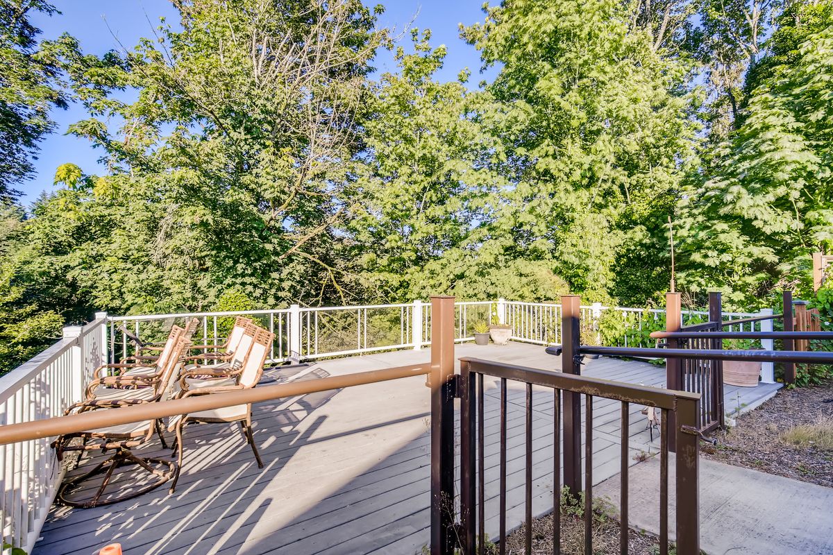 A sunny outdoor deck with patio furniture surrounded by lush greenery.