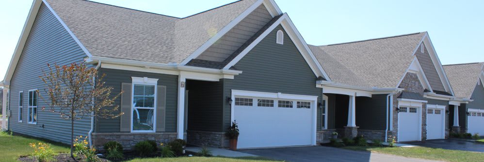 A suburban house with a double garage and green siding.