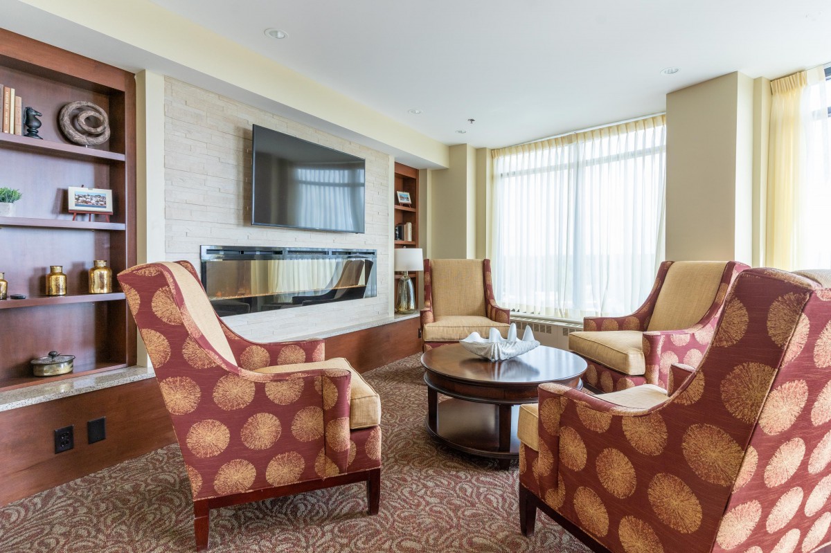 A cozy living room with comfortable seating around a coffee table, featuring a large television and a modern fireplace.