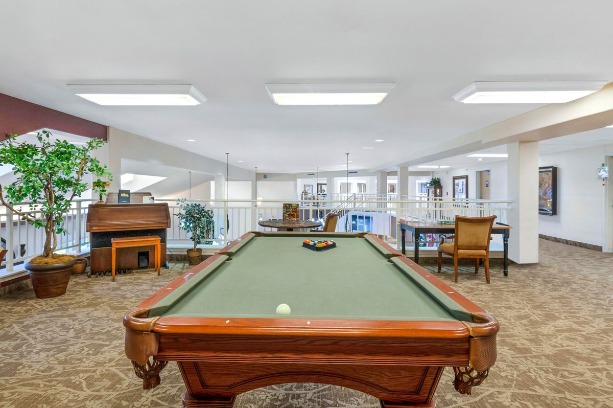 A spacious recreation room featuring a billiard table and various seating options.