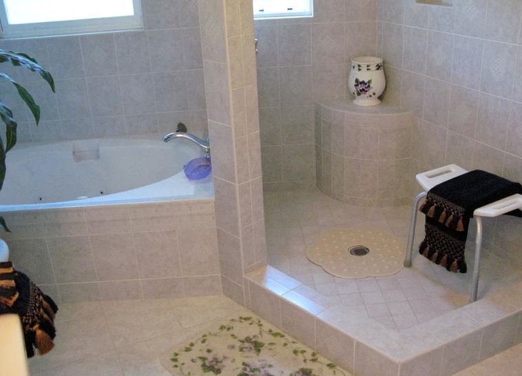 A modern bathroom with a tiled bathtub and shower area.