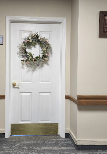 A decorated white door with a floral wreath, set in a beige hallway.