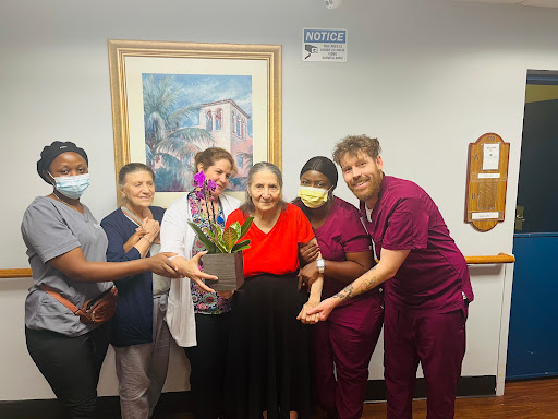 A heartwarming moment of appreciation with healthcare workers and a patient, surrounded by beautiful flowers.
