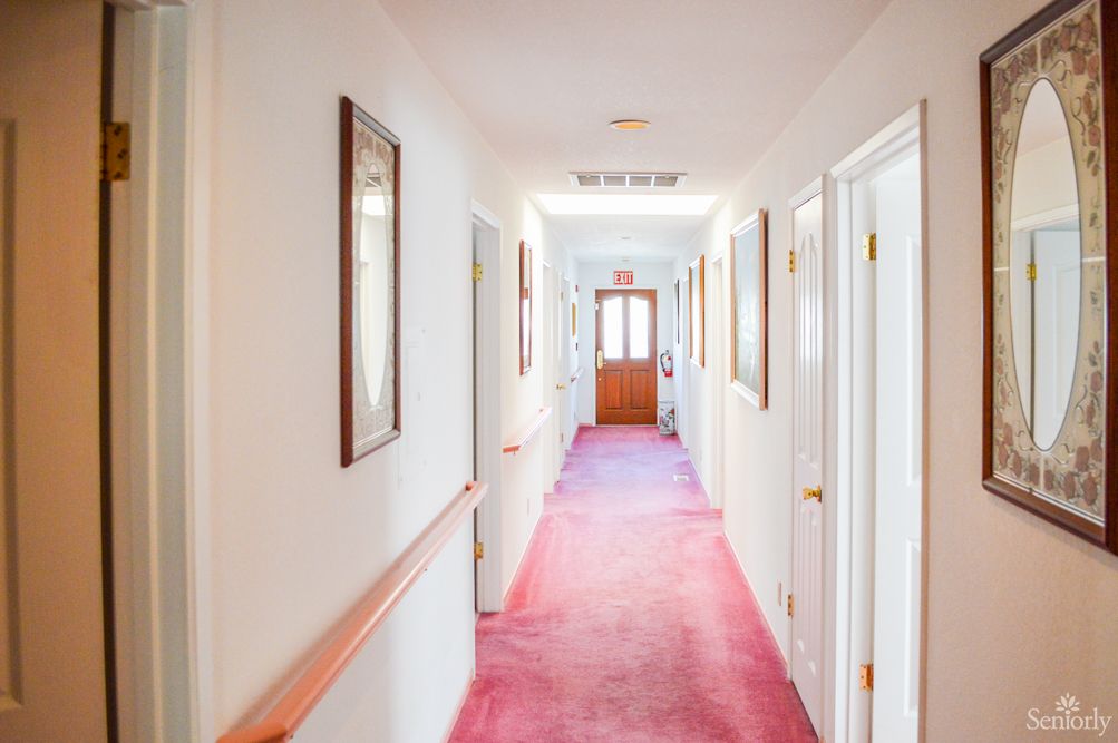 A brightly lit hallway with a red carpet and multiple doors on each side.