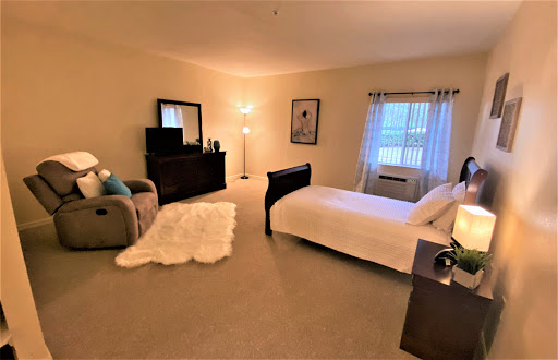 A cozy and modern bedroom featuring a bed, armchair, and natural light filtering through the window.