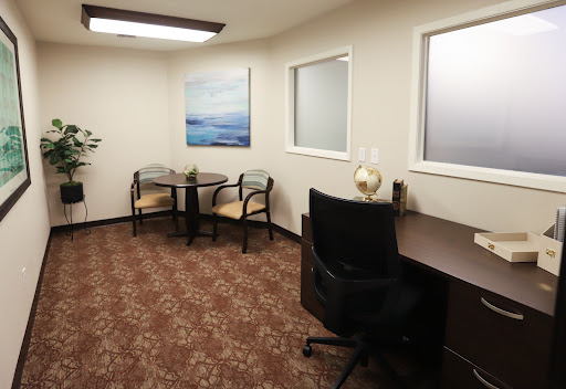 A modern office interior featuring a desk, seating area, and artwork.