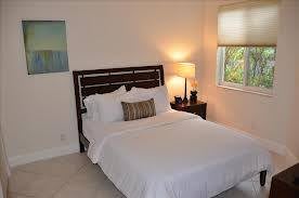 A minimalist bedroom with a neatly made bed, side table, and a lamp by the window.