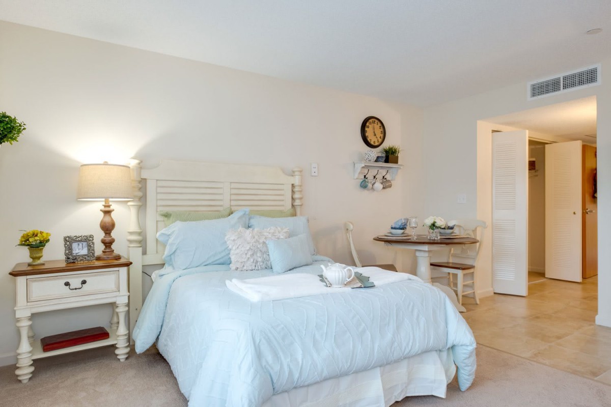 A cozy bedroom with a neatly made bed, soft lighting from a lamp, and elegant decor.