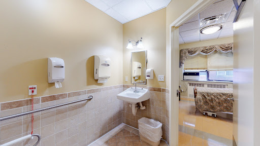 A clean and organized restroom with a sink, toilet, and hand dryers.