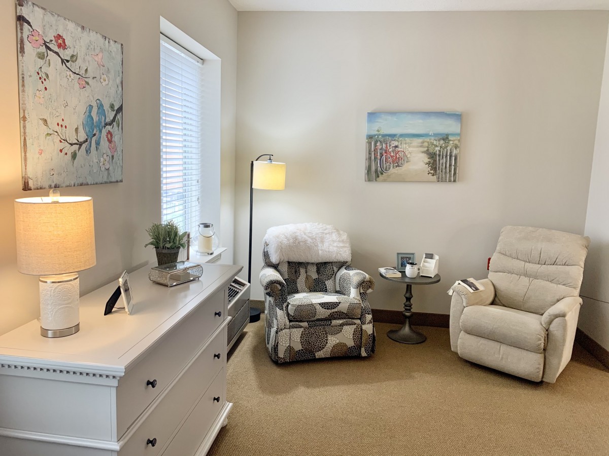A cozy living room corner with an armchair, lamp, and soft decor.