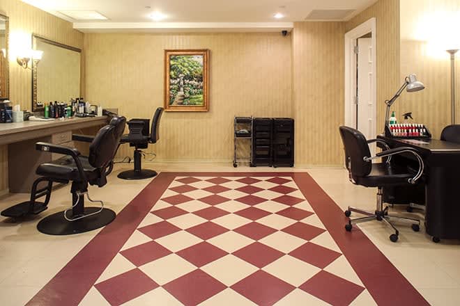 A barbershop interior with checkered flooring and chairs positioned by mirrors.