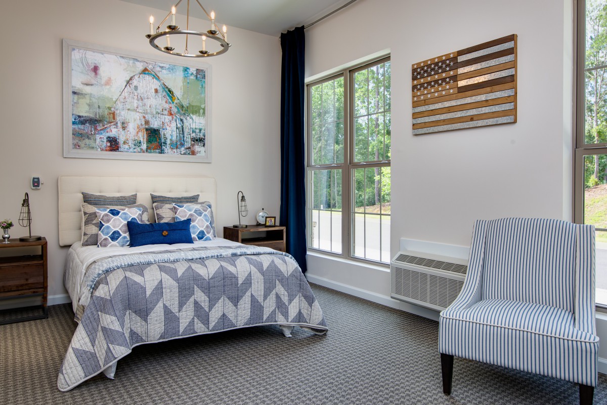 A modern bedroom with stylish decor, featuring a comfortable bed and large window.