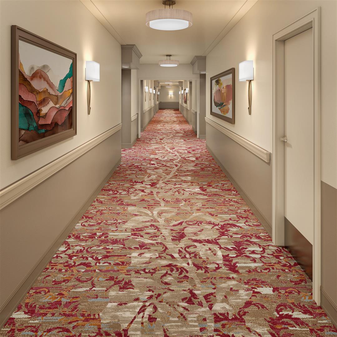 A hotel hallway featuring patterned carpet and artwork on the walls.