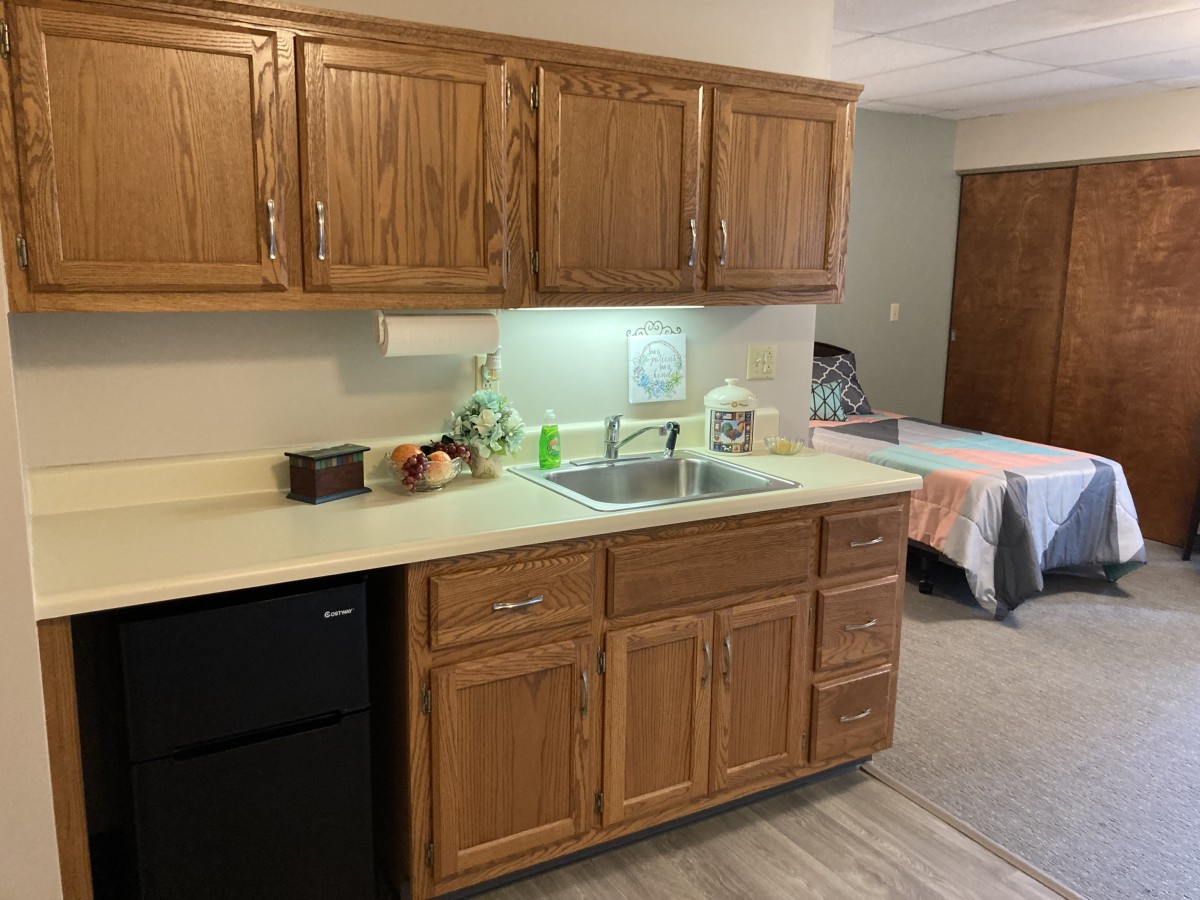 A compact kitchen area with wooden cabinets, a sink, and a countertop.