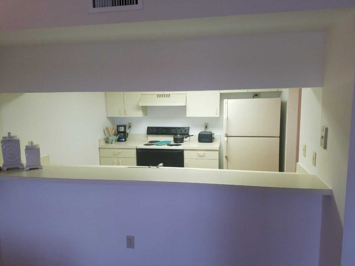 A view of a kitchen with various appliances including a refrigerator, stove, coffee maker, and toaster.