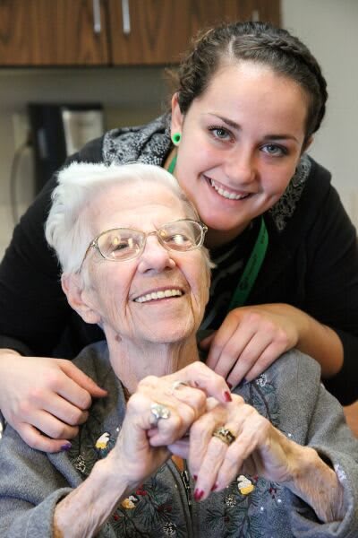 A joyful moment between an elderly person and a young caregiver.