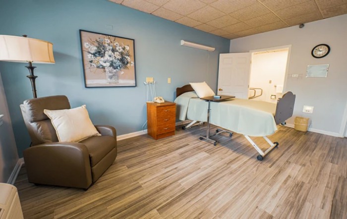 A well-furnished hospital room featuring a medical bed, comfortable chair, and elegant decor.