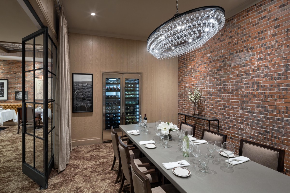 A luxurious dining room with a modern chandelier and elegant table settings.