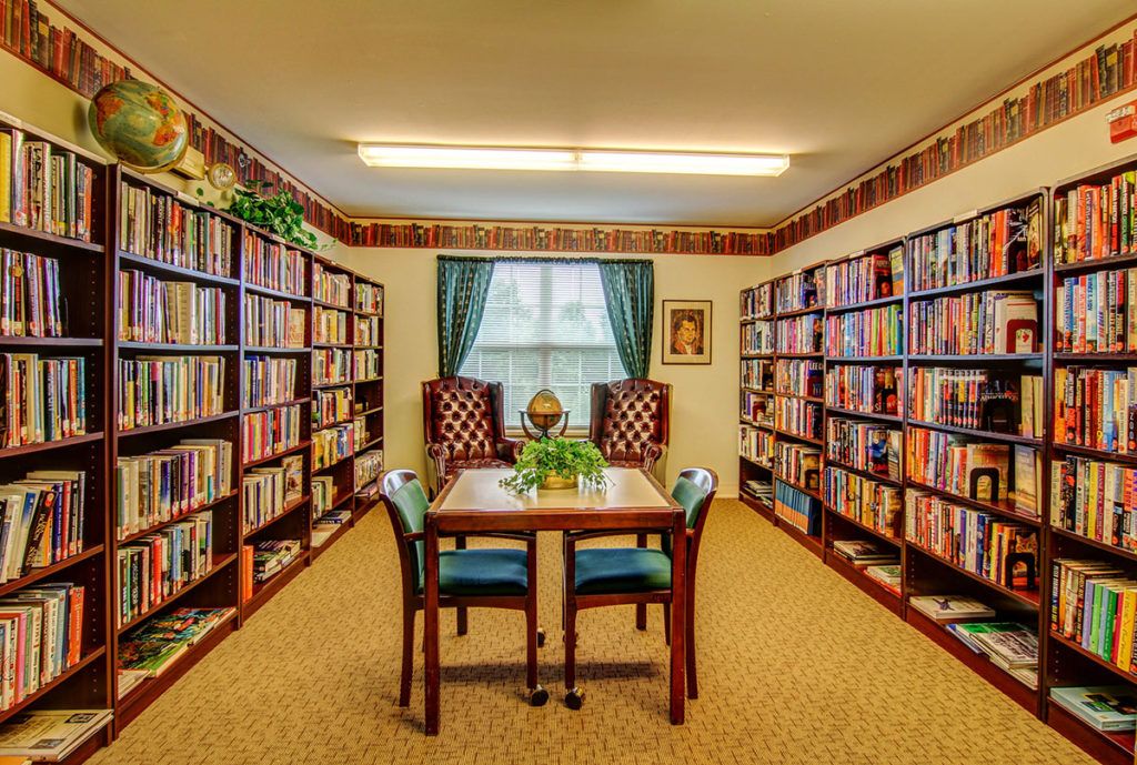 A cozy library reading room with bookshelves, a table, and chairs.