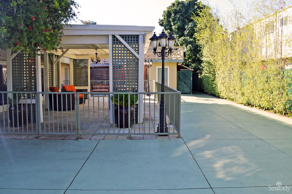 A spacious backyard with a paved area, outdoor seating, and greenery.