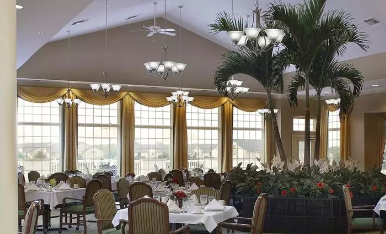 Elegant dining room with large windows, decorative plants, and neatly set tables.