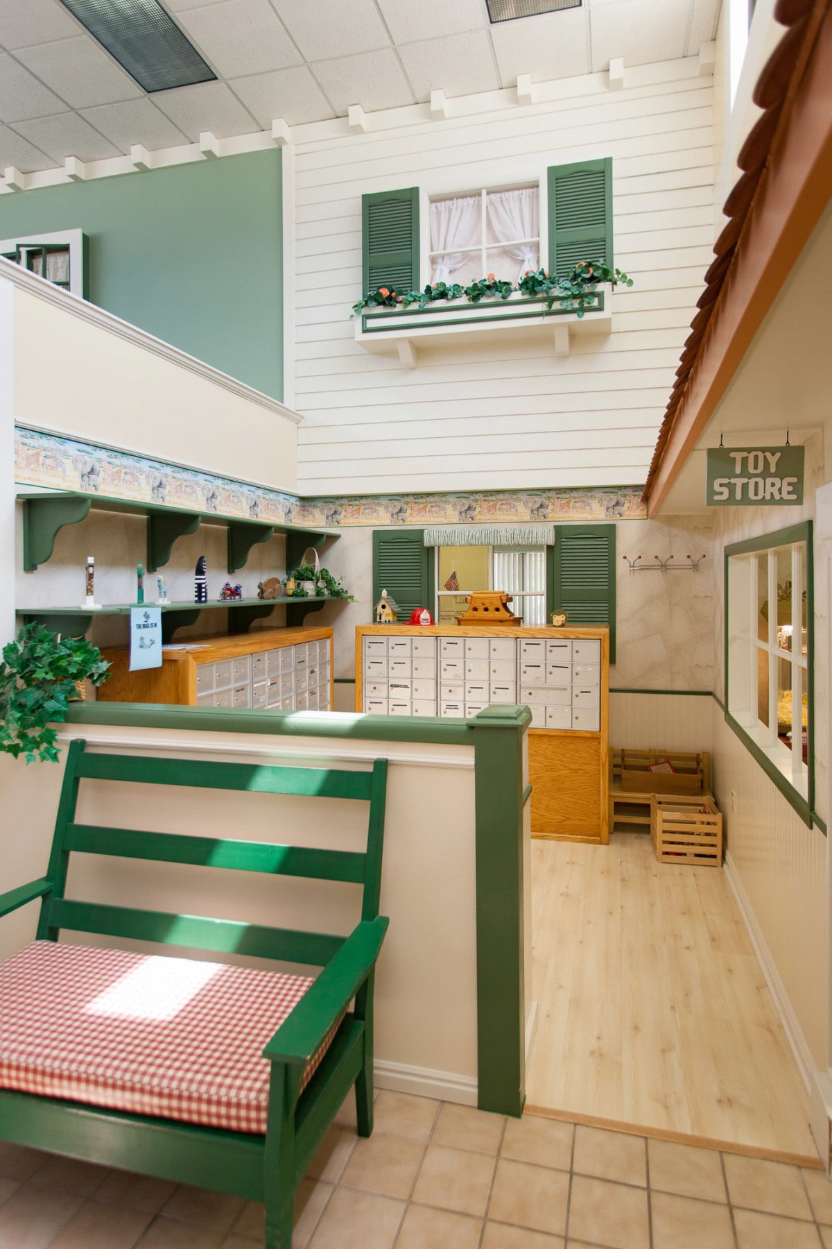 A cozy cafe interior with green benches, wooden floors, and charming window shutters.