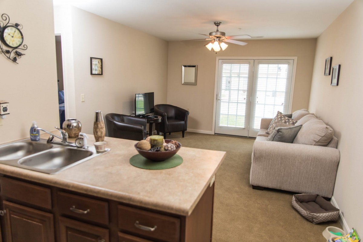 A cozy living room with a sofa, television, and a kitchen island.
