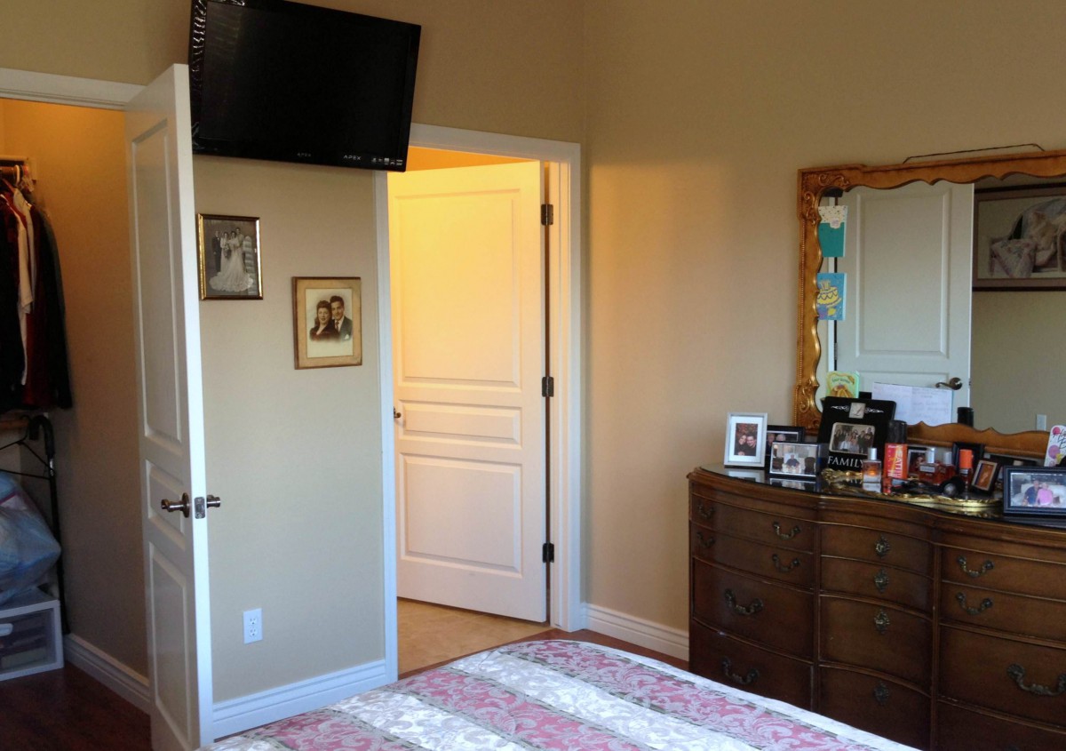 A cozy bedroom with a dresser and a wall-mounted TV.