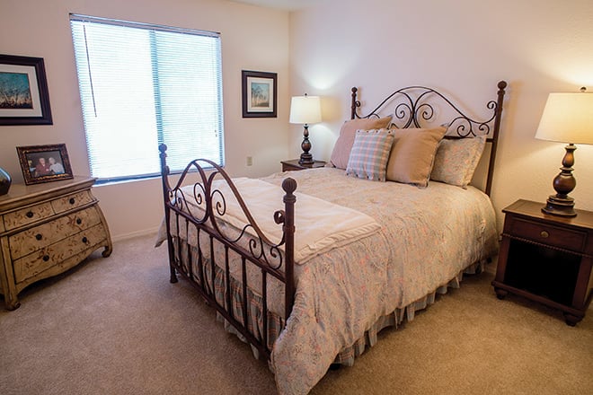 A cozy and elegantly decorated bedroom featuring a wrought iron bed, soft bedding, and warm lighting from a bedside lamp.
