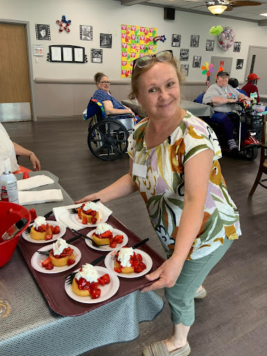 A cheerful volunteer serves delicious strawberry shortcakes at a community gathering.