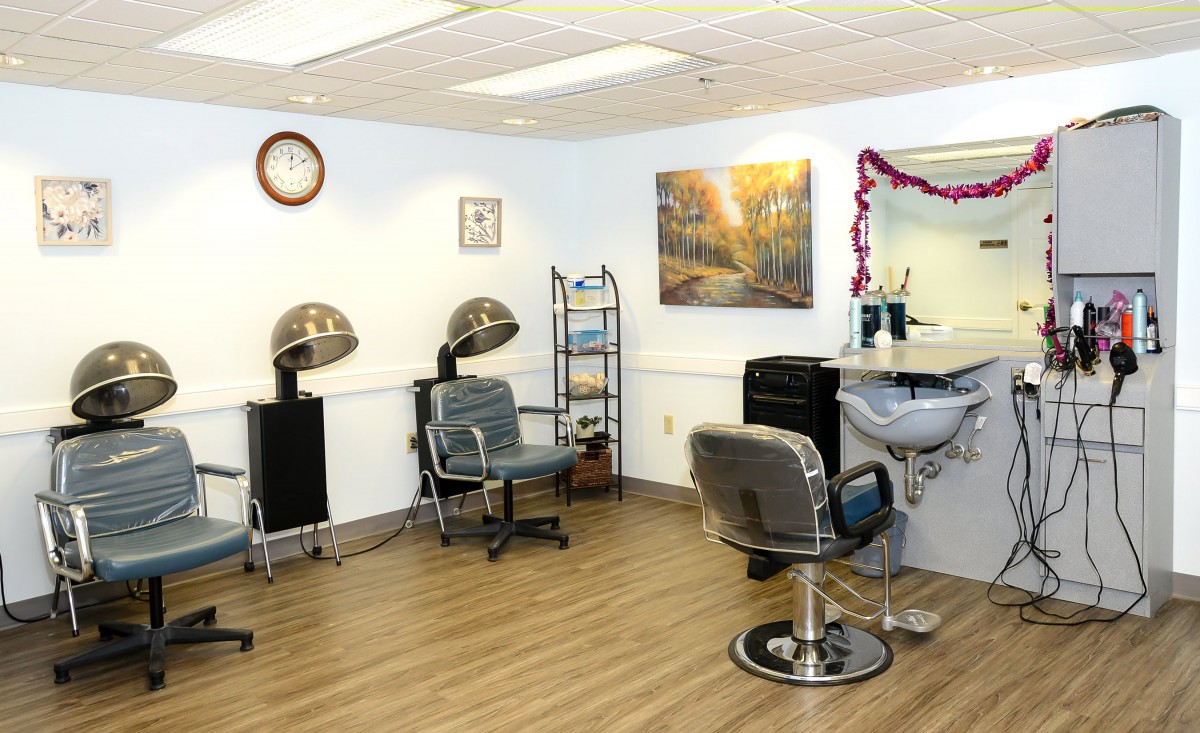 A cozy hair salon interior with chairs, hair dryers, and a mirror.