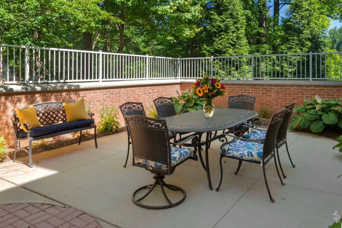 A cozy outdoor patio with a dining set and sunflowers in a vase.