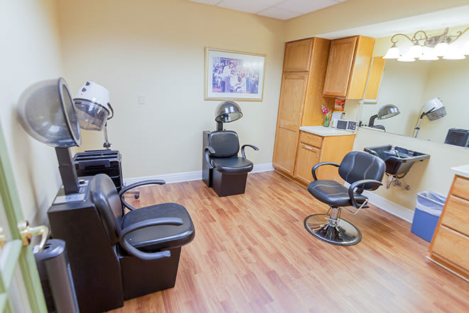 A well-equipped salon interior with chairs, hair dryers, and mirrors on a wooden floor.