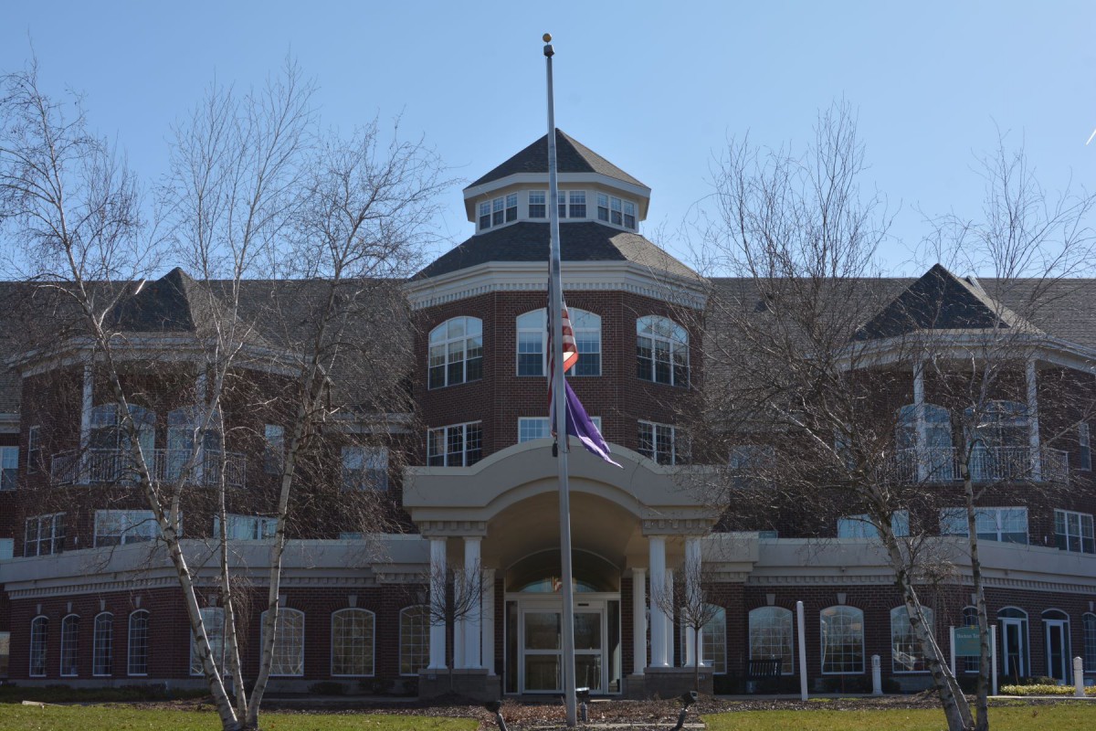 A large brick building with a central entrance and a flagpole in the front.