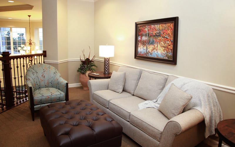 A cozy living room with a sofa, lamp, and artwork on the wall.